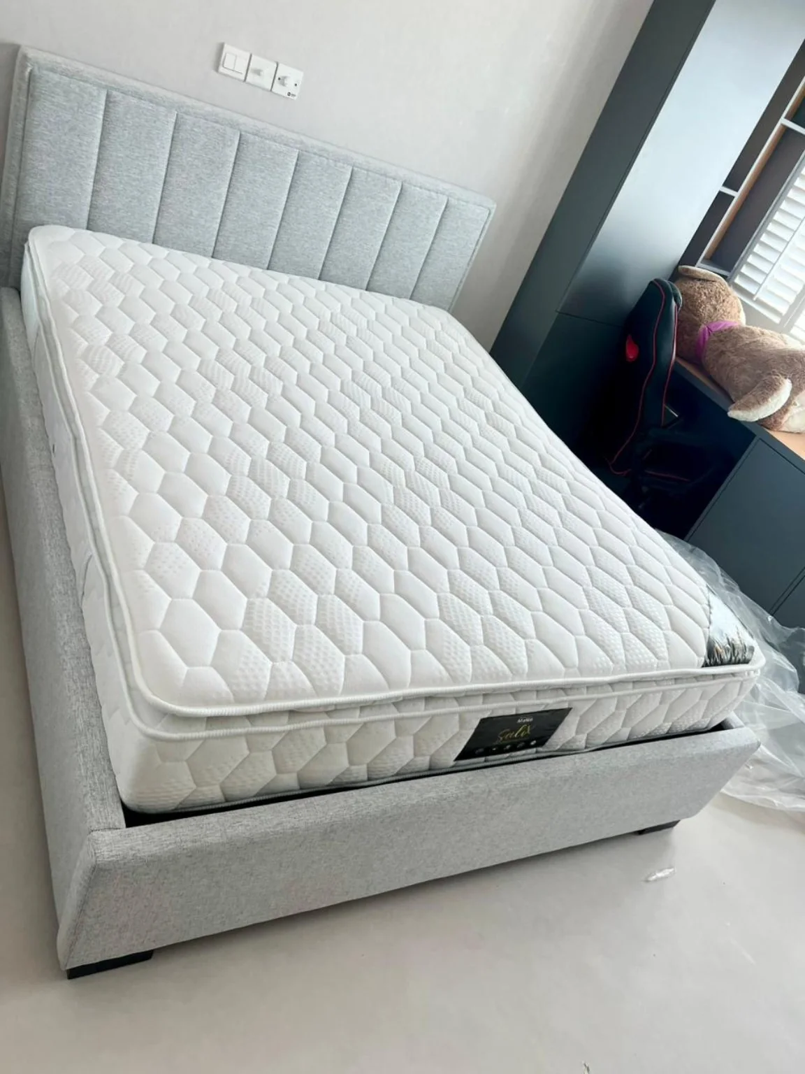 White quilted king-size mattress photographed on a grey upholstered bed